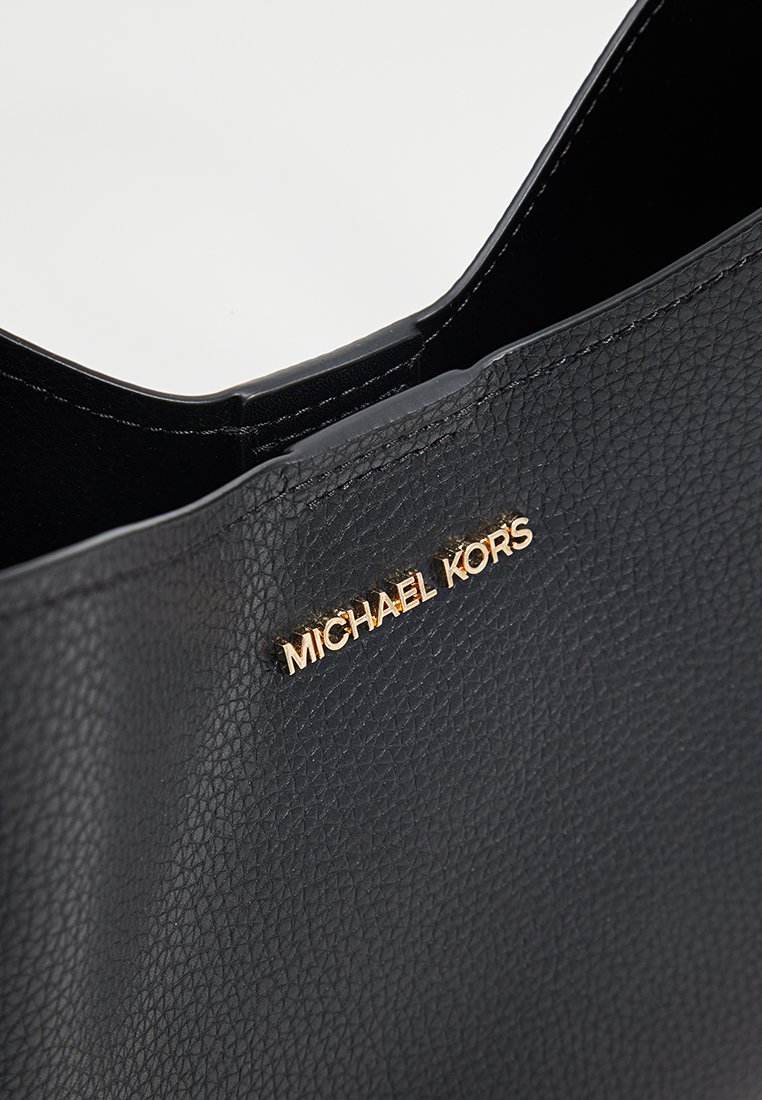 Schwarze, strukturiert aussehende Leder-Tote mit einem goldenen "MICHAEL KORS" Logo-Akzent auf der Vorderseite. Offenes Design, das Innere ist schwarz.
