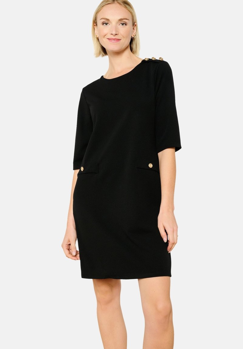 Vestido negro con mangas cortas, dos bolsillos delanteros y botones dorados en los hombros. Tela suave y corte ajustado.