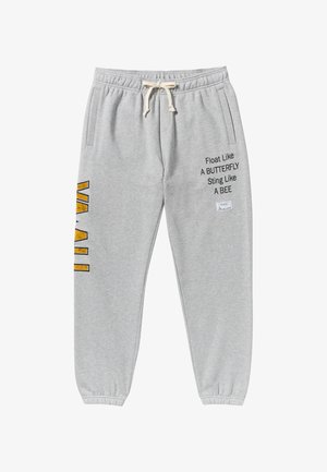 Pantalons de jogging gris en mélange de coton, dotés de poches latérales, d'une taille élastique avec cordon de serrage, et d'imprimés en texte et graphiques en noir et jaune.