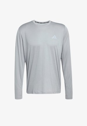 Svetle šedé tričko s dlouhým rukávem z měkké látky s kulatým výstřihem, s jemnými texturovanými proužky a malým bílým logem na hrudi.