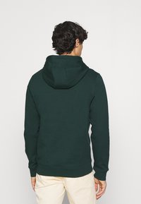 Felpa con cappuccio verde scuro con cordino, polsini e orlo a coste. Realizzata in materiale morbido, presenta un design semplice senza motivi.