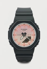 Μαύρο ρολόι χειρός Casio G-Shock με ροζ καντράν, αναλογικούς δείκτες, ψηφιακή οθόνη και μαύρο λουράκι από καουτσούκ.