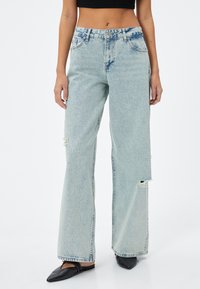 Ljusblå bredbenta jeans i denim, med hög midja och slitna detaljer. Tyget har en mjuk, något urtvättad känsla.