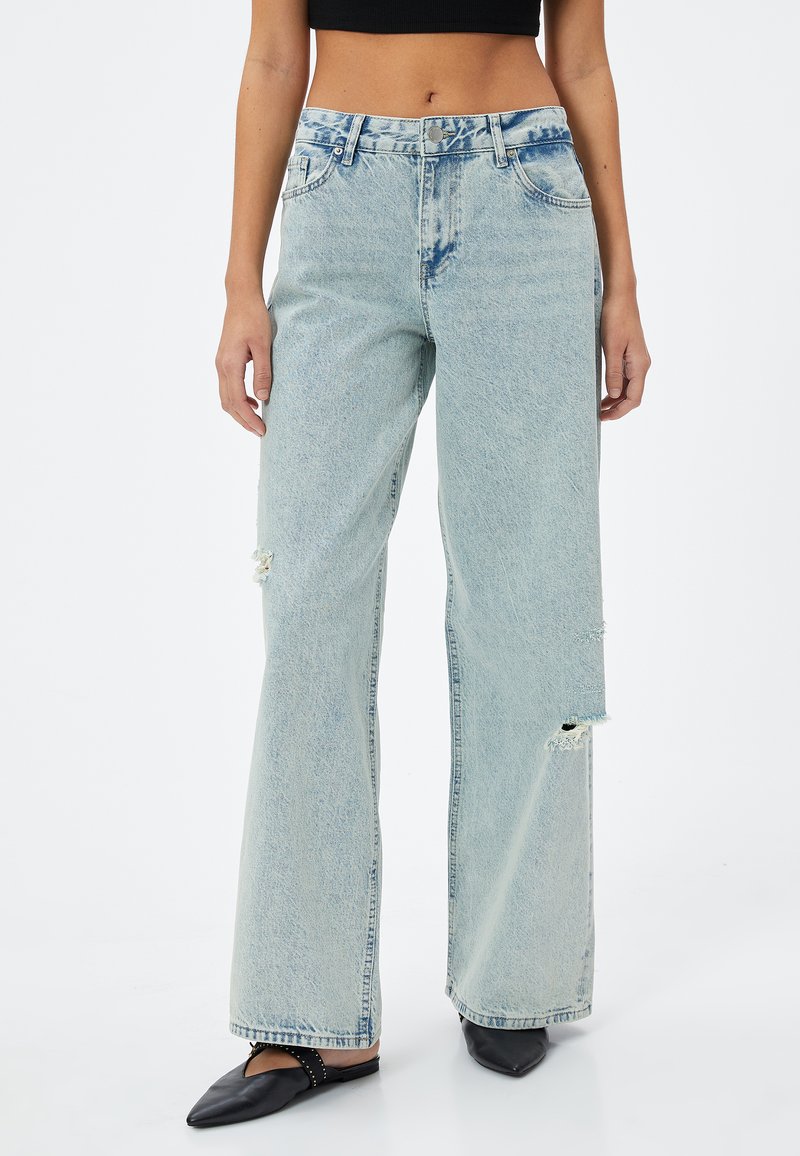 Ljusblå bredbenta jeans i denim, med hög midja och slitna detaljer. Tyget har en mjuk, något urtvättad känsla.