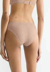 Beige Hipster-Unterwäsche aus glattem, dehnbarem Material. Sie verfügt über einen niedrigen Schnitt und minimale Nähte für eine nahtlose Optik.