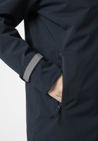Námořnická voděodolná bunda s postranní kapsou na zip a šedým akcentem na manžetě. Hladký povrch s přiléhavým střihem.