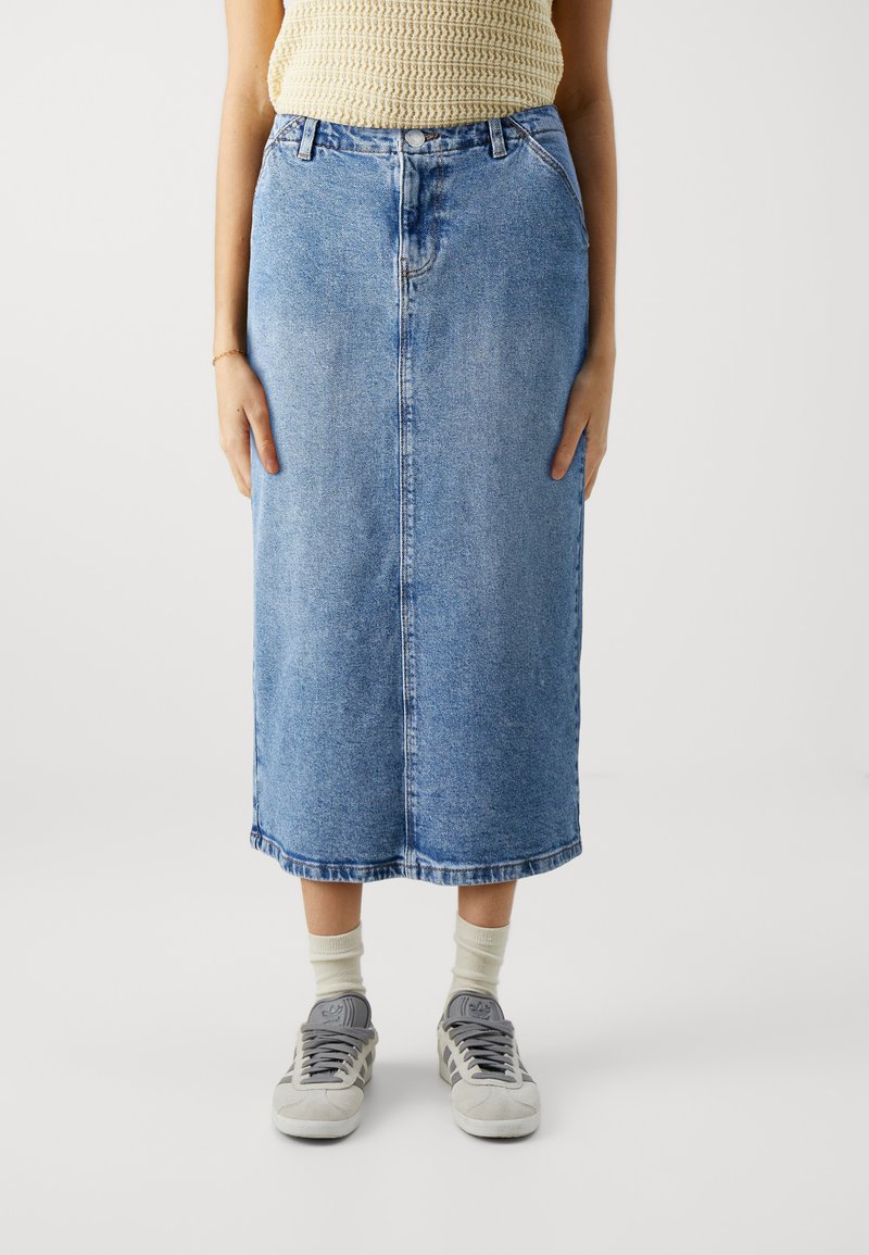 Denim midi seelik, helesinine, kõrge vöökohaga, esise näpunäidisega, kahe küljetaskuga ja sirge lõikega. Koos hallide sneakersitega.