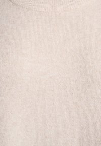 Beige stickad tröja med en mjuk, strukturerad yta och en hög, ribbad halsringning. Enkel design utan ytterligare mönster eller utsmyckningar.
