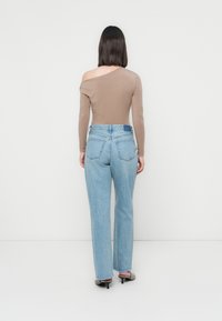 Brun off-shoulder langermet topp kombinert med lyseblå høyt liv rette bukser, med en falmet tekstur og baklommer.