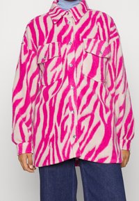 Rosa och krämfärgad oversize skjortjacka i zebramönster, med två framfickor, metallknappar och mjukt, lurvigt material.