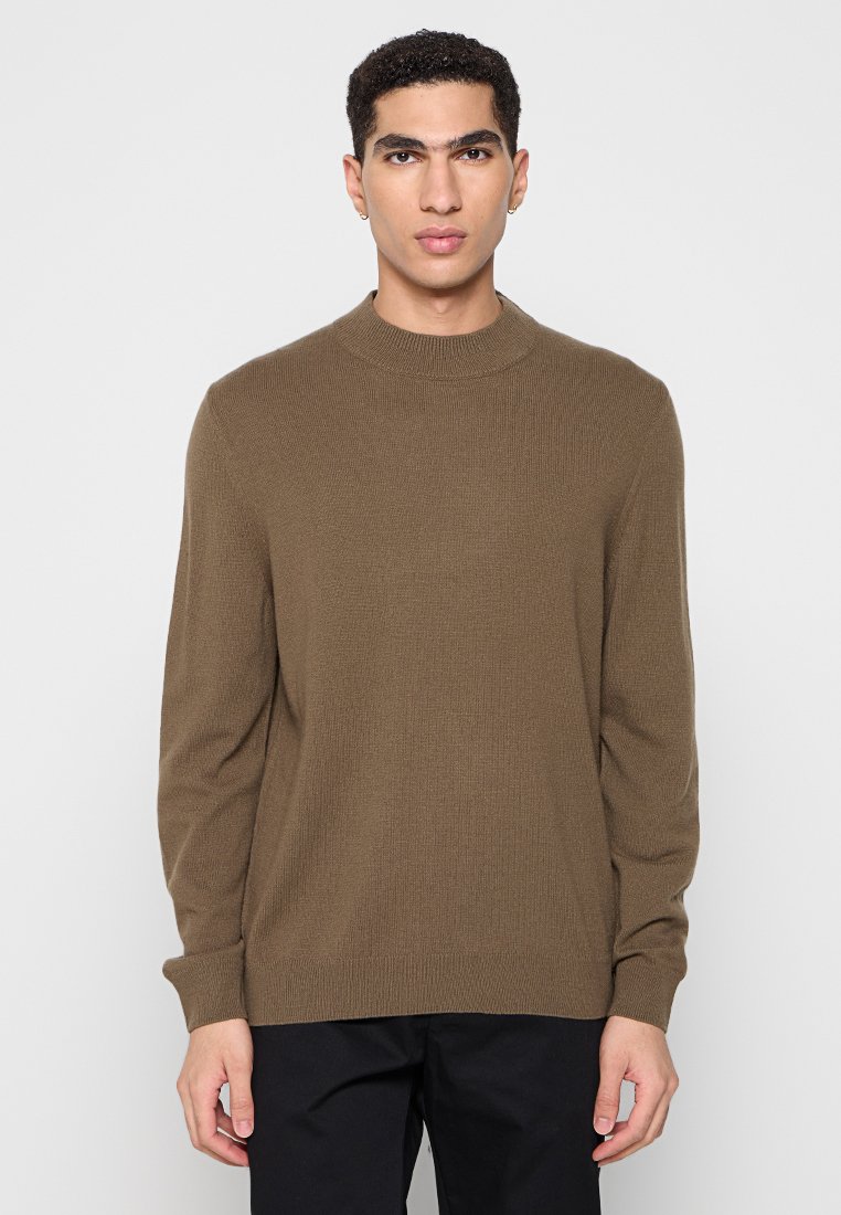 Brauner Strickpullover mit gerippter Textur, Rundhalsausschnitt und langen Ärmeln, kombiniert mit dunklen Hosen. Minimalistisches Design und taillierte Passform.