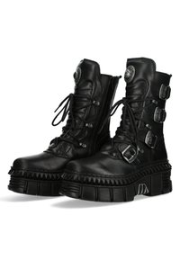 Black leather platform boots with lace-up front, three adjustable buckles, ribbed sole, and a textured finish. Rounded toe and side zipper.