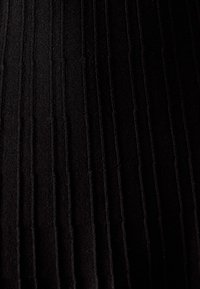 Čierny plisovaný textil s vertikálnymi ryhami, vytvárajúci textúrovaný vzhľad. Materiál je mäkký s jemným leskom, pričom zdôrazňuje hľbku a detaily.