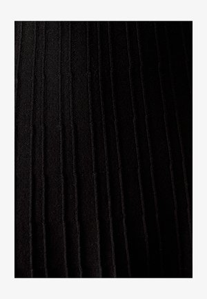 Mustat laskostetut tekstiilit, joissa on pystysuorat urat, luovat tekstuuria. Materiaali on pehmeä ja siinä on hiukan satiinimaisuutta, mikä korostaa syvyyttä ja yksityiskohtia.