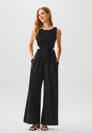 Černý overal s přiléhavým živůtkem, širokými nohavicemi, bočními výřezy a kapsami. Hladká textura látky a kulatý výstřih.