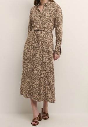 Pitkähihaisen, napillisen mekon beigen ja ruskean leopardikuvion kanssa. Varustettu vyötärölle kiristettävällä vyöllä ja keskikokoisella leikkauksella. Sileä kankaan rakenne.