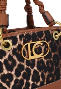 Sac à main imprimé léopard avec accents en cuir marron, poignées tressées, garnitures dorées et un logo proéminent sur le devant.