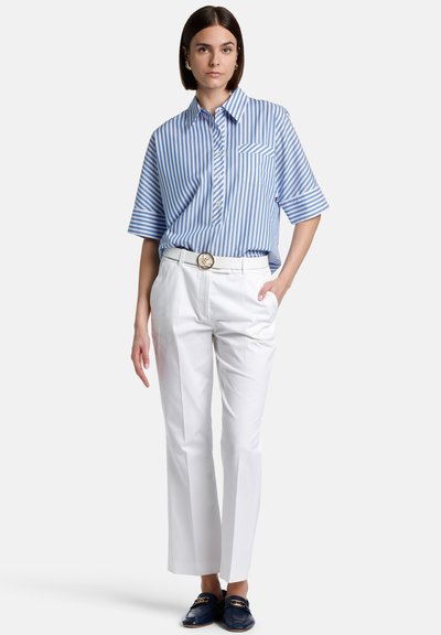 Blue and white striped short-sleeve shirt, white tailored pants, and dark loafers with a gold accent. Features a chest pocket and belt detail.