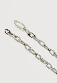 Sudraba metāla ķēde ar maiņām ovālām un taisnstūrveida saitēm, ar spīdīgu apdari un drošu sprādzi vienā galā.