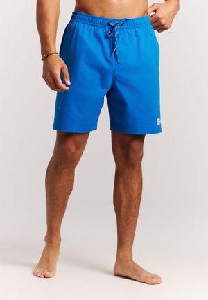 Man draagt felblauwe zwemshort met trekkoord, staat blootsvoets tegen een effen achtergrond en toont voor- en zijaanzicht.