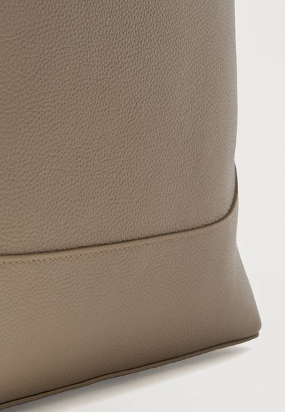 Κοντινή λήψη μιας μπεζ υφής δερμάτινης επιφάνειας με οριζόντια ραφή κοντά στο κάτω άκρο.