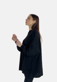 Maglione nero over-size a maglia con collo alto e maniche voluminose, realizzato in un tessuto testurizzato e dalla vestibilità ampia.