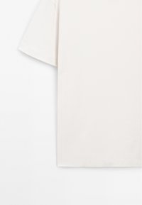 Ljusbeige t-shirt med korta ärmar i mjuk bomull, med en avslappnad passform och en enkel fåll utan extra mönster eller detaljer.