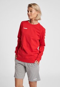 Rode sweatshirt met lange mouwen, geribbelde manchetten en ronde halslijn, gecombineerd met grijze shorts. Bevat een wit logo op beide items.
