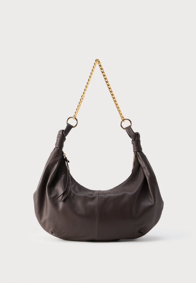 Μαλακή σκούρα καφέ δερμάτινη τσάντα ώμου με δεμένα άκρα και κοντή χρυσή αλυσίδα, πάνω σε απλό φωτεινό φόντο.