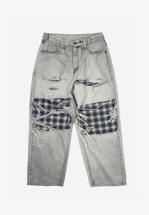 Ανοιχτό γκρι τζιν παντελόνι με μεγάλες φθαρμένες τρύπες στους μηρούς, που αποκαλύπτουν μαύρα και λευκά καρώ υφασμάτινα μπαλώματα από κάτω.