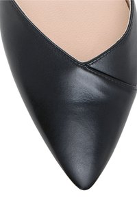 Chaussure plate en cuir noir à bout pointu avec empeigne en forme de V et doublure intérieure beige.