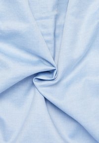 Lichtblauwe stof met een gladde textuur, weergegeven in een gedraaide opstelling. Bevat een subtiele diagonale ribbelpatroon.