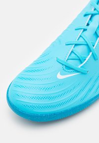 Scarpa da atletica turchese con cima testurizzata, sistema di lacci sottile e suola in gomma liscia. Presenta un logo bianco e una leggera lucentezza.