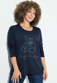T-shirt a maniche lunghe blu navy con un grafica di orsetto e testo "Buon Natale" in grigio chiaro. Tessuto morbido con una vestibilità comoda.