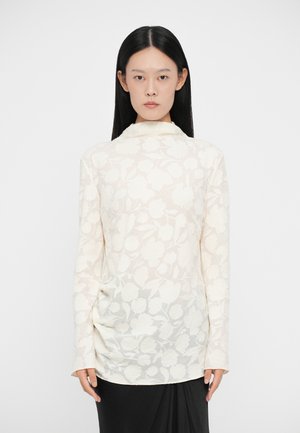 Lang mouw shirt in lichtcrème met bloemenpatroon, semi-transparante textuur, hoge kraag en een getailleerd silhouet.
