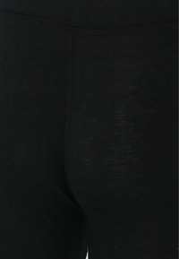 Leggings noirs avec une texture lisse, présentant un design simple et une coupe ajustée. La taille cousue renforce la durabilité et la flexibilité.