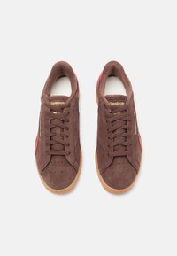 Brune anilinsneakers med rosa og røde detaljer, rund tå, perforerte detaljer og såle i gummi. Inkluderer gulllogo på tungen.