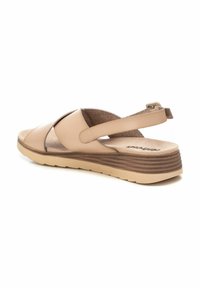 Sandal beige con design a fasce incrociate, cinturino posteriore regolabile, soletta imbottita e suola intermedia testurizzata con accenti marroni a strati.