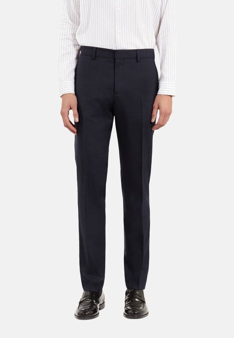 Marineblauwe broek van gladde stof; slim fit; beschikt over twee voorzakken; gecombineerd met glanzende zwarte schoenen en een wit gestreept shirt.