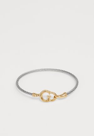 Silver cable-style bracelet with gold-tone clasp featuring a 'G' logo, smooth texture, and subtle detailing along the edges.