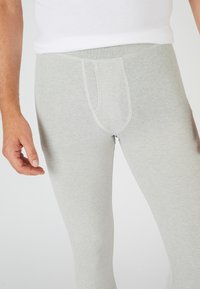 Leggings ajustados en gris claro, fabricados en una suave mezcla de algodón, con un diseño de bolsillo frontal, costuras planas y una cinturilla elástica para mayor comodidad.