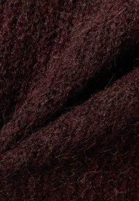 Close-up van donker bordeauxrood gebreid wollen stof met zichtbare vezels en getextureerde patronen.