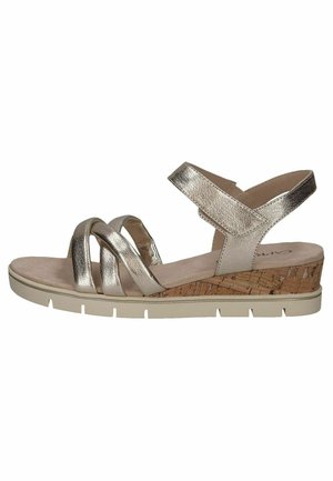 Sandales dorées métalliques avec des brides croisées, talon en liège, semelle beige et texture lisse. Arrière fermé avec une sangle de cheville ajustable.