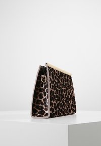 Kabelka ve vzoru leopardí kůže s lesklým zlatým kováním na horní části, strukturovaným semišovým materiálem a bočním zipem s kovovým kruhovým zdobením.