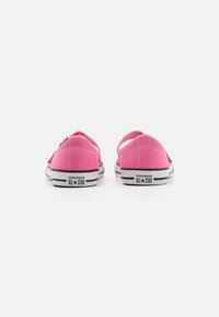 Roze platnene tenisice s bijelim vezicama i crnim gumenim potplatima. Imaju nisku dizajniranu siluetu, šivane detalje i "Converse All Star" logo na peti.