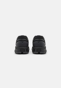 Baskets de sport noires avec une tige texturée et des semelles épaisses et crantées. Elles sont dotées d'un col rembourré et d'un logo au talon.