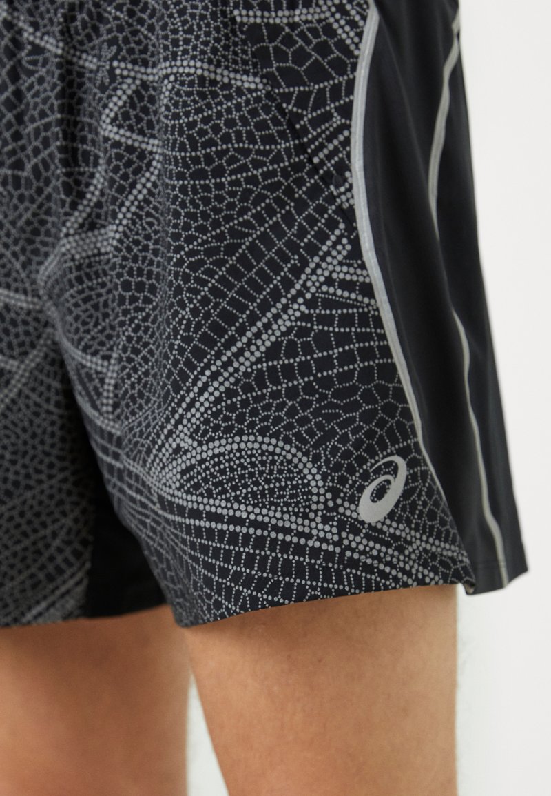 Pantalones cortos deportivos negros con un patrón geométrico plateado, que presentan un logo en la parte inferior izquierda y acentos reflectantes a lo largo de las costuras.