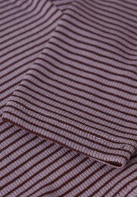 Tissu rayé dans des nuances de lavande et de bordeaux, présentant une texture côtelée et des bords repliés, soulignant de délicates coutures.