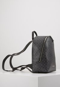 Plecak Calvin Klein w czarnym teksturowanym materiale z wzorem logo na całej powierzchni, bocznym zamkiem błyskawicznym i regulowanymi paskami.