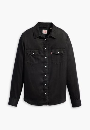 Chemise en denim noir à manches longues, fermeture à boutons, deux poches poitrine et col classique. Présente une surface texturée et des boutons blancs.